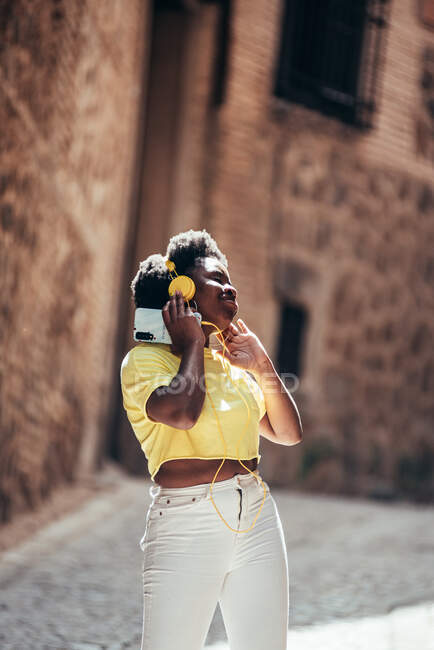 Retrato de menina negra com cabelo afro apreciando a música e dançando em uma rua da cidade velha. — Fotografia de Stock