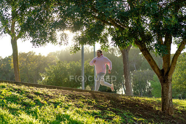 Gros homme sprint dans le parc avec la lumière du coucher du soleil — Photo de stock