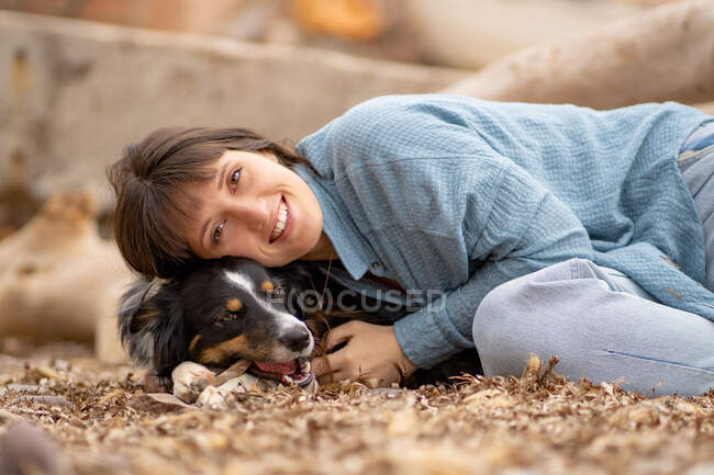 Wunderschönes hellhäutiges Mädchen, das lächelnd auf ihrem Hund am Strand liegt — Stockfoto