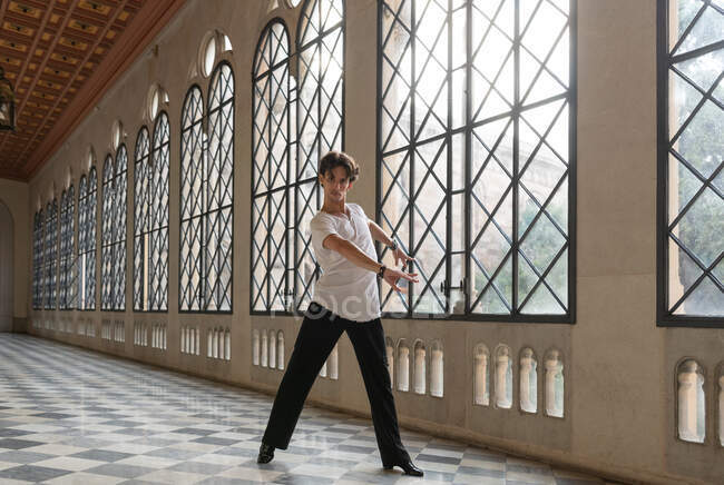 Slim man dancing in spacious ornamental ballroom during Latin dance rehearsal — Stock Photo