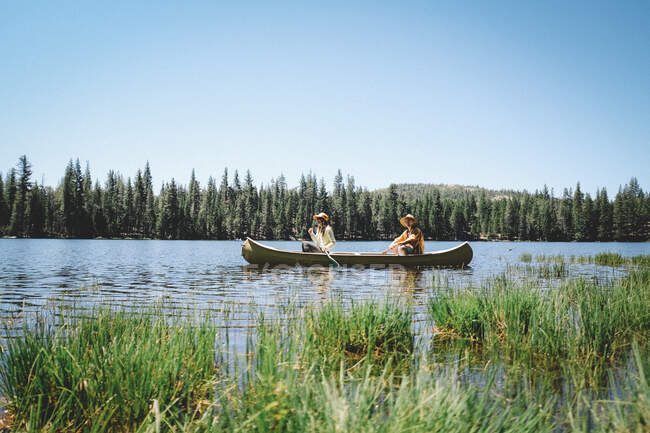 Madre e hijo reman juntos en una canoa amarilla. Lago Scenic Sierra. - foto de stock