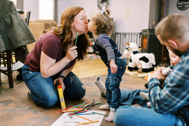 Tout-petit fille embrasser sa mère tout en coloriant sur le sol — Photo de stock
