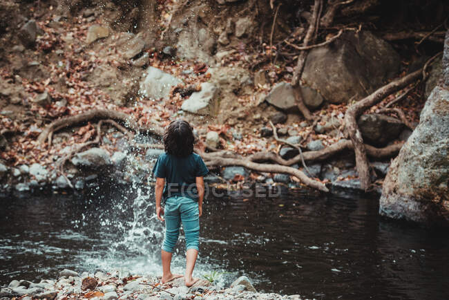 Niño disfrutando en la orilla de un río - foto de stock