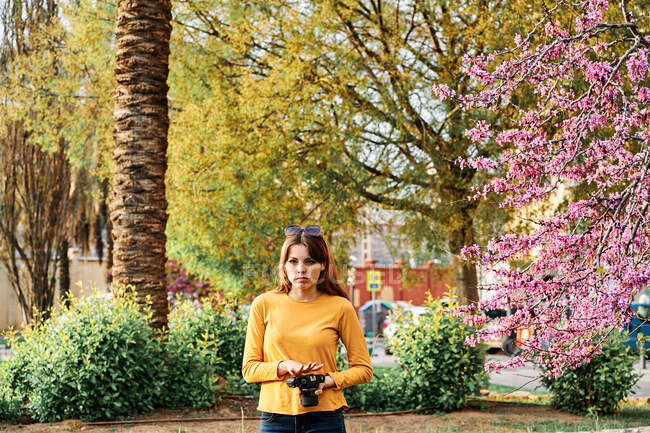 Chica joven caminando en el parque con una cámara fotográfica en primavera - foto de stock