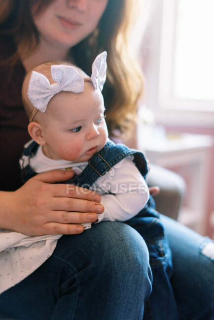 Little baby being burped in her mothers arms by window light — Stock Photo