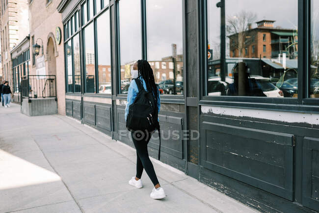 Молодая черная женщина в маске во время ковида 19 пандемии в городе — стоковое фото