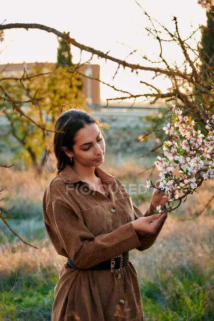 Portrait of a young woman touching the flowers of an almond tree — Stock Photo