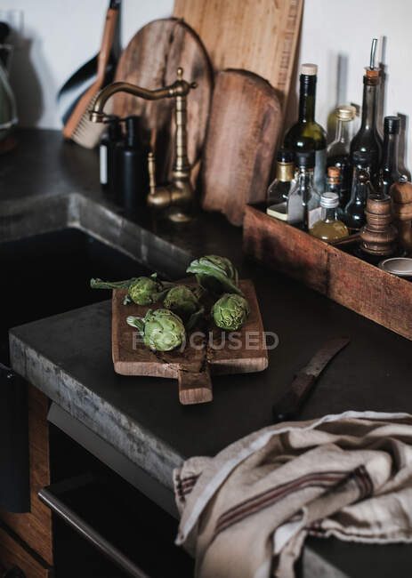 Свежие артишоки овощи и кран на деревянный стол — стоковое фото