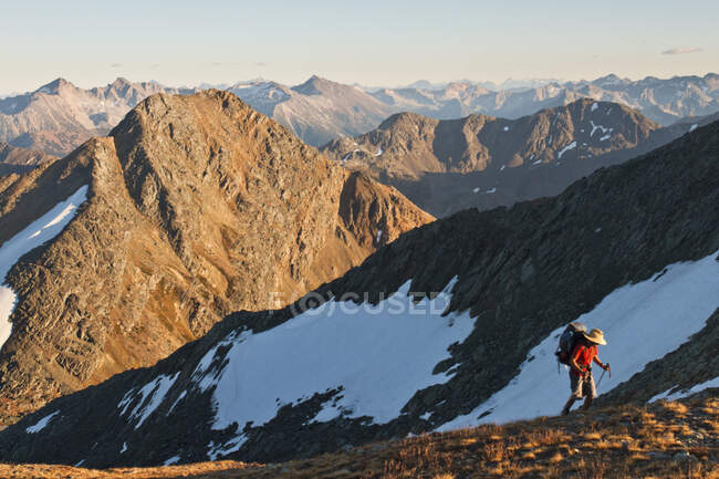 A backpacker is illuminated by evening light, scenic mountain view. — Stock Photo
