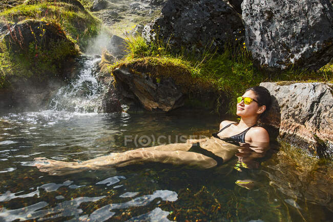 Junge Frau im Badeanzug mit Wasserfall in den Bergen — Stockfoto