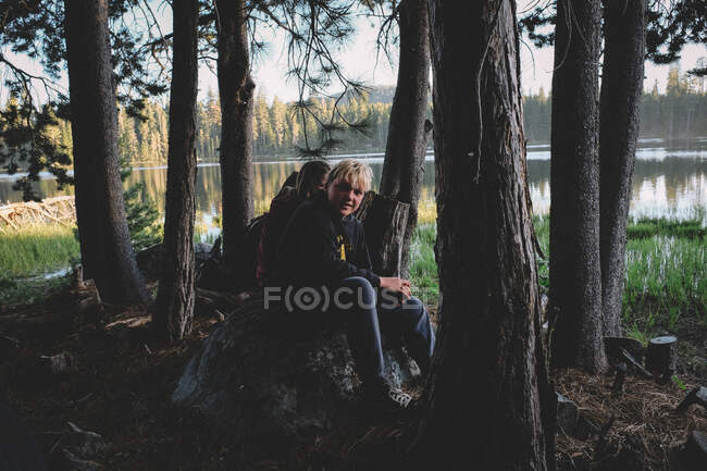 Adolescente chico disfruta de un momento pacífico en el bosque al atardecer - foto de stock