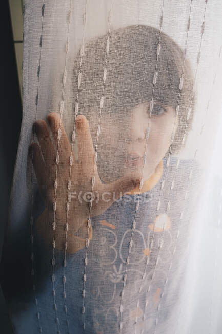Niño jugando detrás de la cortina - foto de stock