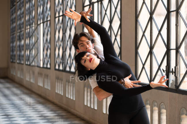 Homme et femme pratiquant une danse passionnée avec les bras levés dans une élégante salle de bal — Photo de stock