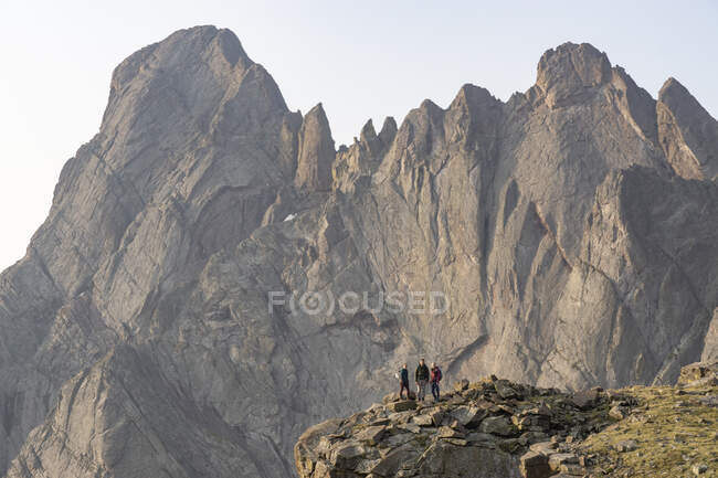 Male and female backpackers standing against rocky cliff while backpacking during vacation — Stock Photo