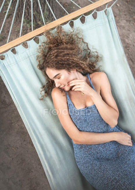 Retrato de una hermosa chica de moda con el pelo rizado en una d azul - foto de stock