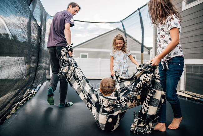 Family jumping on a trampoline in the backyard — Stock Photo