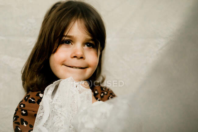 Молода дівчина тримається на мереживній завісі посміхаючись — стокове фото