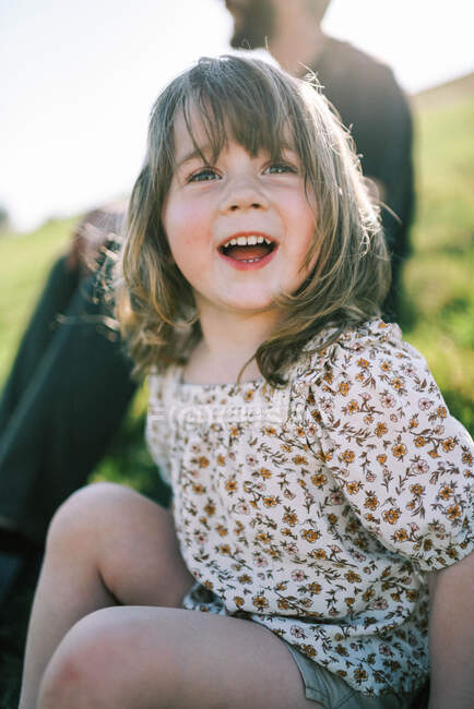 Pequena menina criança feliz rindo enquanto o sol brilha em sua cabeça — Fotografia de Stock