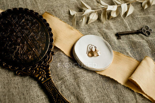 Colocación plana de un par de pendientes en un plato de anillo con baratijas vintage - foto de stock