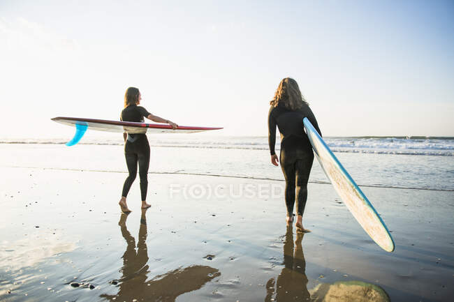 Two women friends going for a sunrise summer surf — Stock Photo