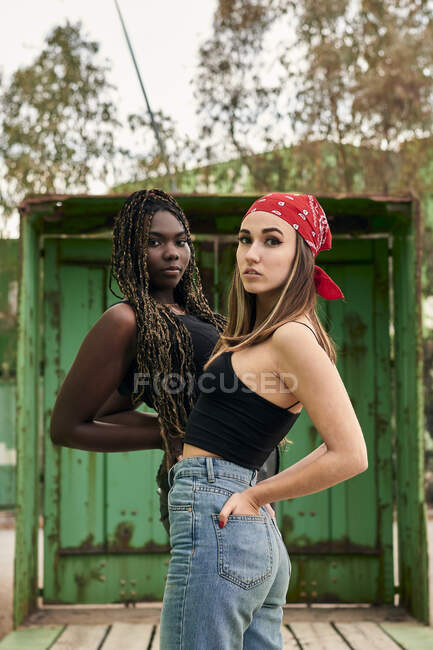 Dos mujeres multiétnicas con ropa urbana posando mirando a la cámara - foto de stock