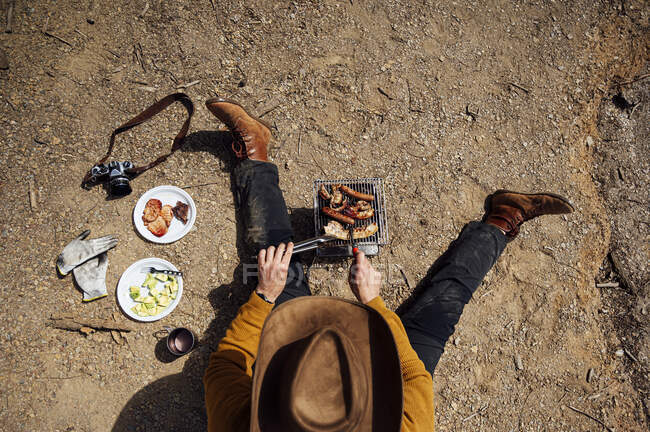 Young man doing a barbecue in the field. — Stock Photo