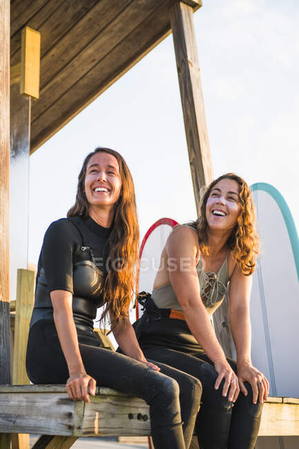 Dos amigas sonriendo antes del amanecer surf de verano - foto de stock