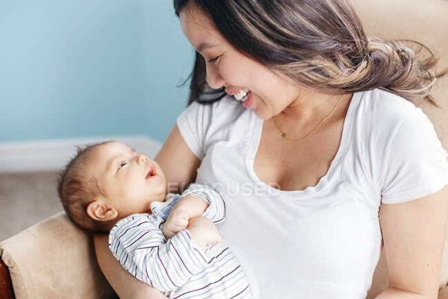 Mothers day holiday. Proud smiling Chinese Asian mother holding rocking newborn infant baby son. Home lifestyle authentic natural moment. Bonding of mom and child. Ethnic diversity — Stock Photo
