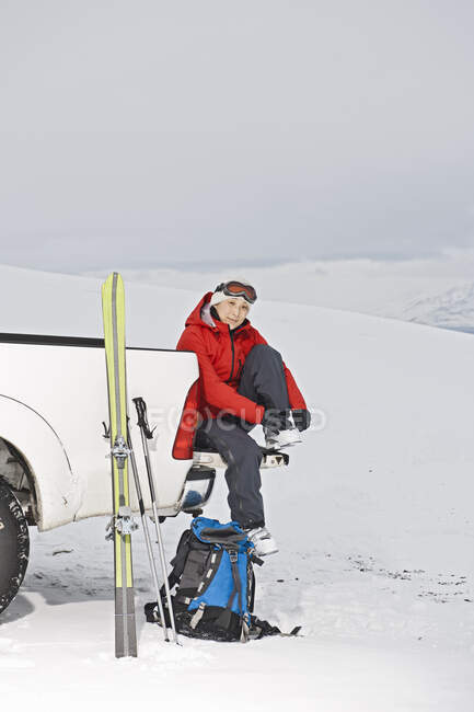 Frau sitzt auf dem Rücksitz eines Pick-ups und macht eine Pause vom Skifahren — Stockfoto