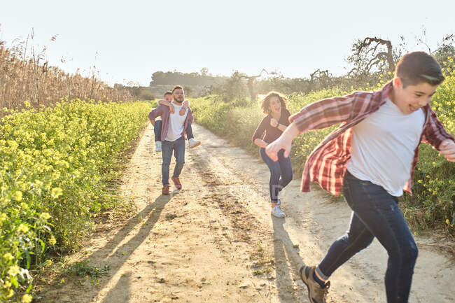 Happy family runs through the countryside in spring — Stock Photo