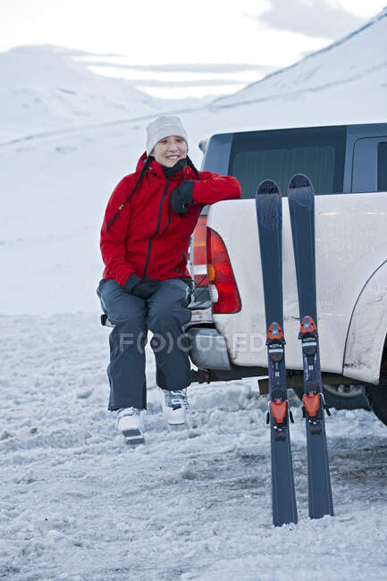 Woman sitting on the back of pick up truck taking a break from skiing — Stock Photo