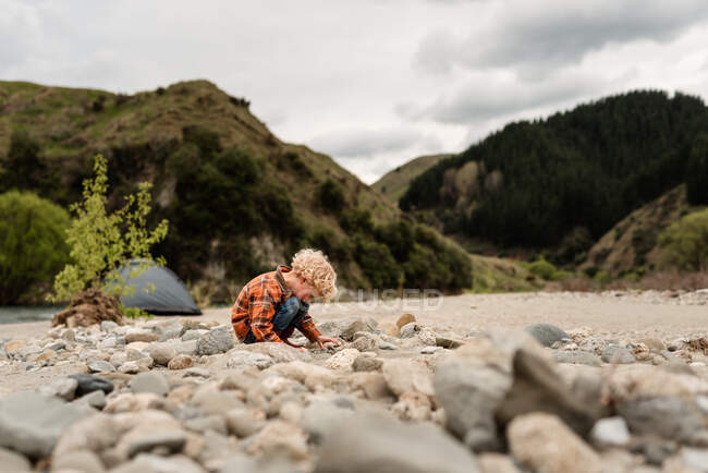 Молодой кудрявый ребенок смотрит на каменные окаменелости в Новой Зеландии — стоковое фото