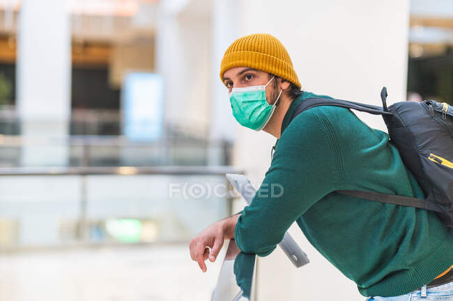 Uomo spagnolo moderno con maschera protettiva verde nel centro commerciale — Foto stock