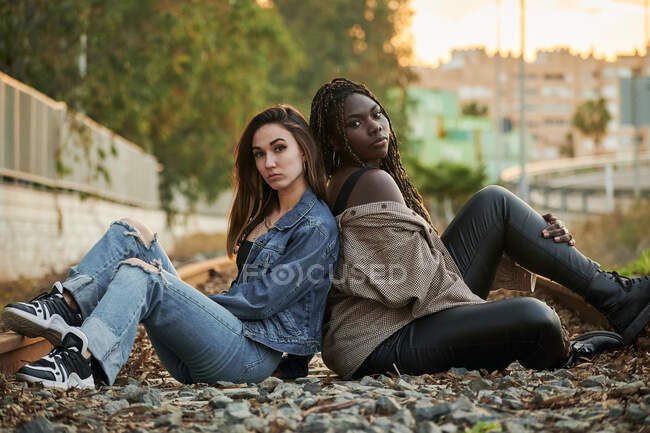 Zwei multiethnische junge Frauen posieren und blicken bei Sonnenuntergang in die Kamera — Stockfoto