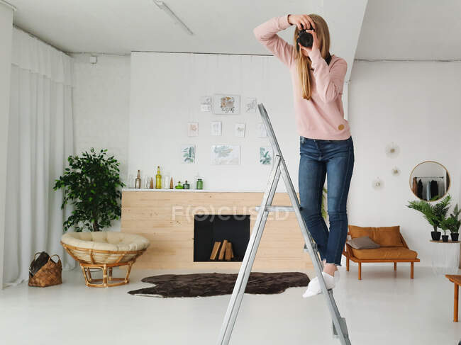 Junge blonde Fotografin macht Foto auf der Leiter — Stockfoto