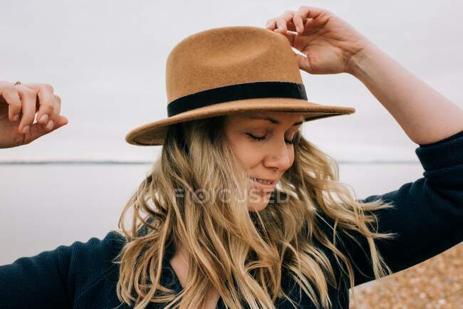 Donna in piedi sulla spiaggia con il vento che soffia i capelli e gli occhi chiusi — Foto stock