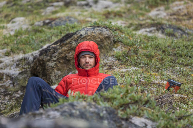 Portrait of a mountaineer wearing a red down jacket. — Stock Photo