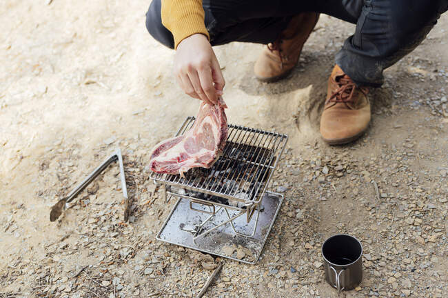 Uomo mettendo carne sul barbecue — Foto stock