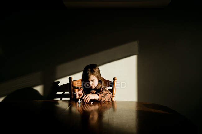 Jeune fille dans un pull jouant avec des jouets une table de cuisine dans sa maison — Photo de stock
