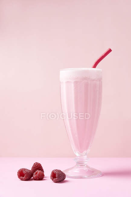 Frullato di lamponi servito in un bicchiere da dessert con una paglia metallica ecologica riutilizzabile, accompagnato da frutta fresca. — Foto stock