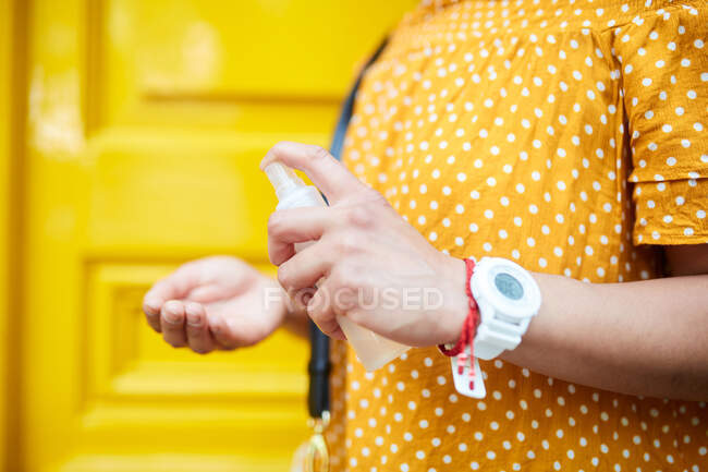 Femme méconnaissable appliquant pulvérisation antibactérienne sur ses mains — Photo de stock