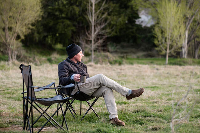 Mann mittleren Alters hält Tasse Kaffee auf Campingplatz — Stockfoto