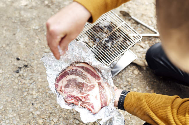 Barbecue man putting salt on meat — Stock Photo
