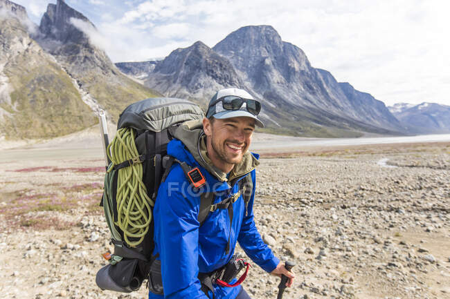 Smiling backpacker wearing rain jacket in mountain pass. — Stock Photo
