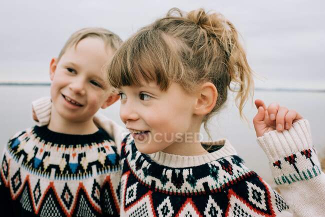 Hermano y hermana jugando y abrazándose en la playa juntos en otoño - foto de stock