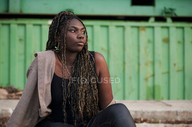 Черная женщина в городской одежде сидит на заброшенных рельсах — стоковое фото