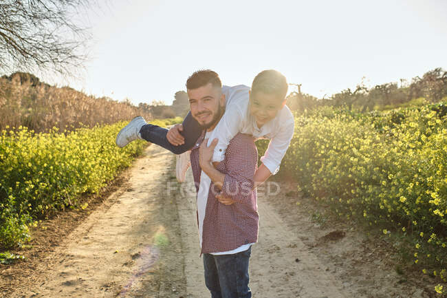 Pai feliz olha para a câmera enquanto brincava com seu filho no campo — Fotografia de Stock