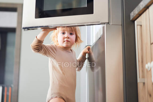 Рыжеволосый ребенок смотрит в холодильник. в поисках пищи — стоковое фото