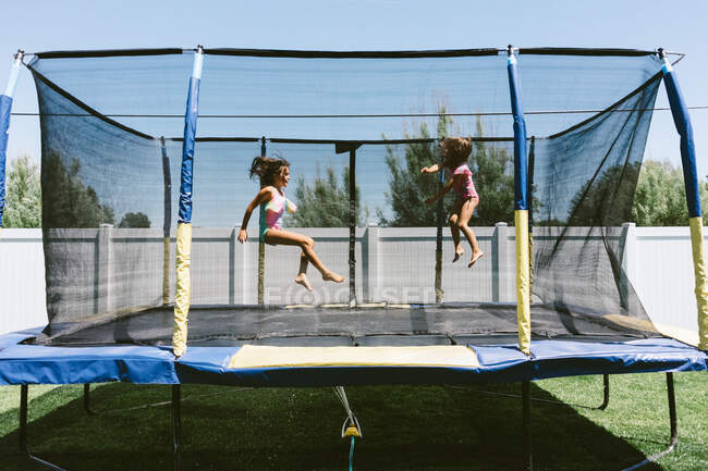 Schwestern genießen Sommer auf dem Trampolin mit Sprinkler — Stockfoto
