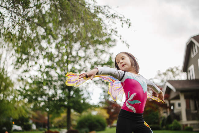 Ein kleines Mädchen spielt draußen in Schmetterlingsflügeln mit ausgestreckten Armen — Stockfoto